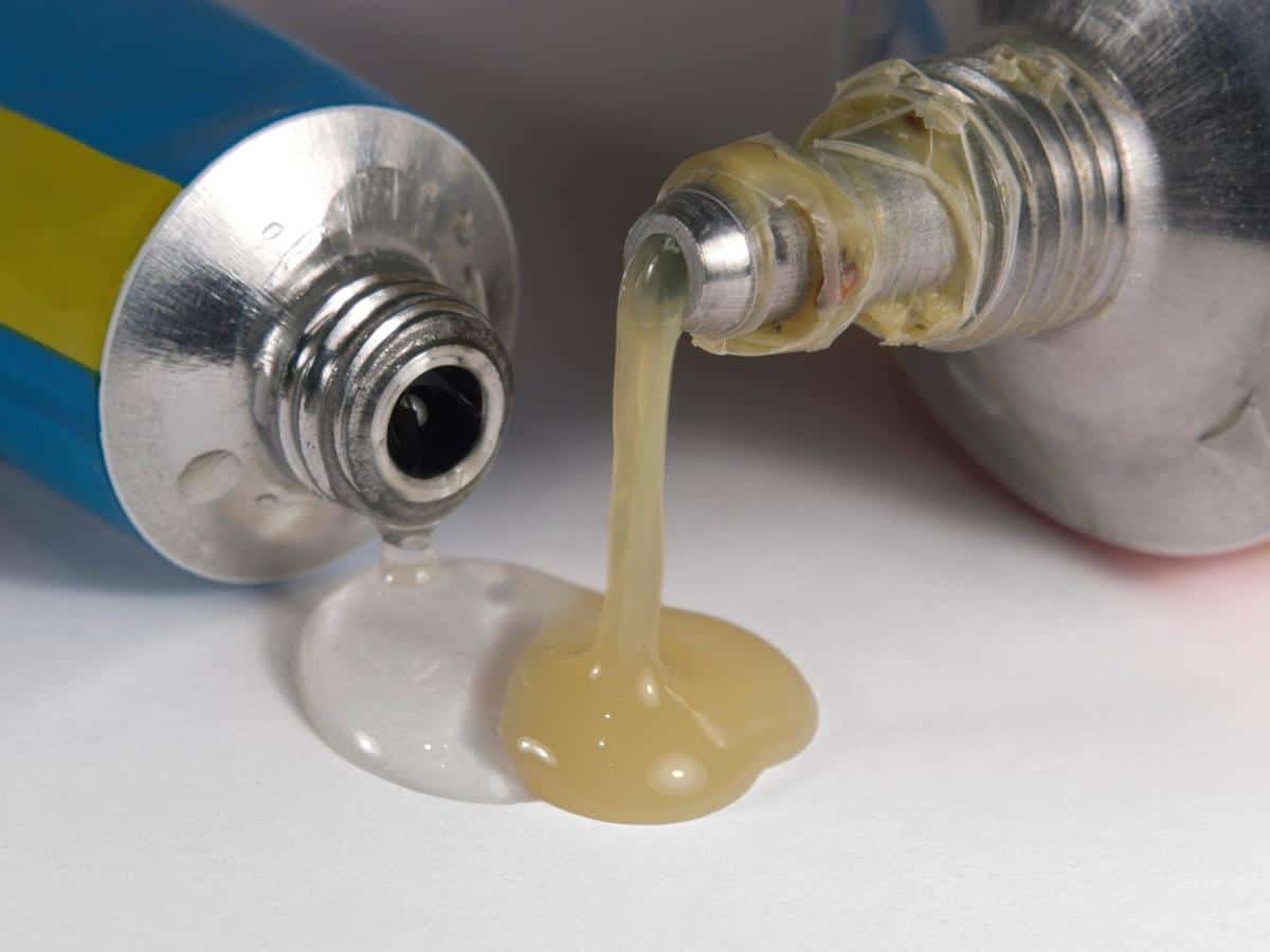 studio photography of two emplastic tube tips and flowing glue