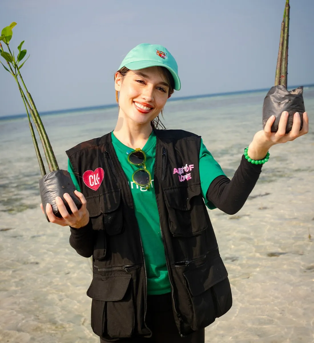 Cinta Laura tengah memegang dua pohon mangrove yang akan ditanamnya di Pulau Pari._